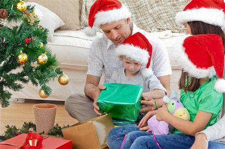 father christmas family portrait - Happy family looking at the little boy opening a christmas present in the living room Photographie de stock - Aubaine LD & Abonnement, Code: 400-04296618