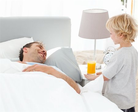 Cute boy bringing the breakfast to his father lying on the bed at home Stock Photo - Budget Royalty-Free & Subscription, Code: 400-04296652