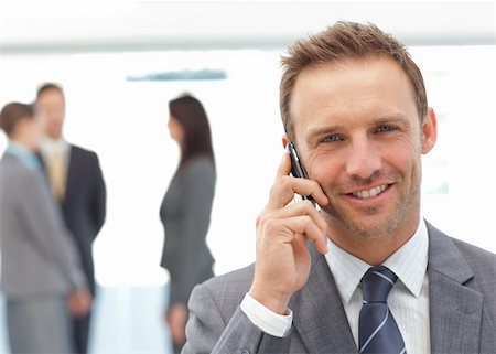 simsearch:400-04287075,k - Happy businessman on the phone while his team working on the background Fotografie stock - Microstock e Abbonamento, Codice: 400-04296705