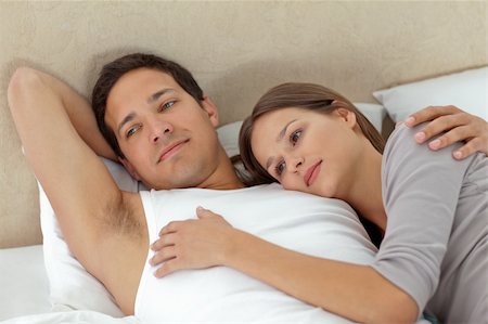 sleeping bed full body - Pensive couple lying in each other's arms on their bed Stock Photo - Budget Royalty-Free & Subscription, Code: 400-04296709