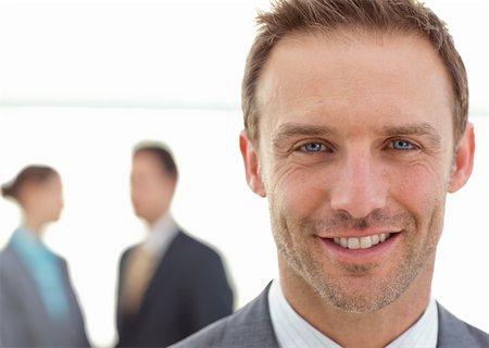 simsearch:400-04287075,k - Cheerful businessman posing in front of his team while working on the background Fotografie stock - Microstock e Abbonamento, Codice: 400-04296717