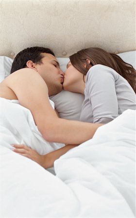 sleeping bed full body - Adorable couple kissing while relaxing on the bed at home Stock Photo - Budget Royalty-Free & Subscription, Code: 400-04296736