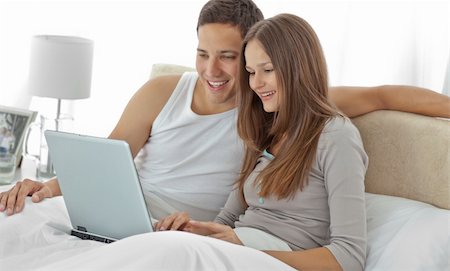 Young couple watching a video on the laptop lying on their bed Stock Photo - Budget Royalty-Free & Subscription, Code: 400-04296737