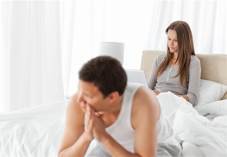 simsearch:649-03487806,k - Woman working on the laptop while her boyfriend is worrying sitting on the edge of the bed Stock Photo - Budget Royalty-Free & Subscription, Code: 400-04296753
