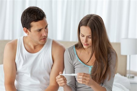 Worried couple looking at a pregnancy test sitting on their bed at home Stock Photo - Budget Royalty-Free & Subscription, Code: 400-04296765