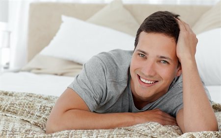 Joyful man lying on th edge of his bed at home and looking at the camera Stock Photo - Budget Royalty-Free & Subscription, Code: 400-04296882