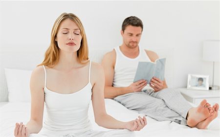 simsearch:400-04335941,k - Woman practicing yoga while her husband is reading on the bed Stock Photo - Budget Royalty-Free & Subscription, Code: 400-04296931