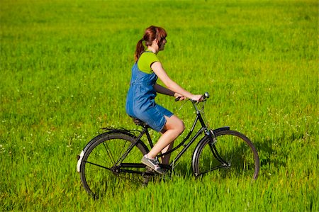 simsearch:400-04201795,k - Happy young woman on a green meadow riding a bicycle Fotografie stock - Microstock e Abbonamento, Codice: 400-04290911