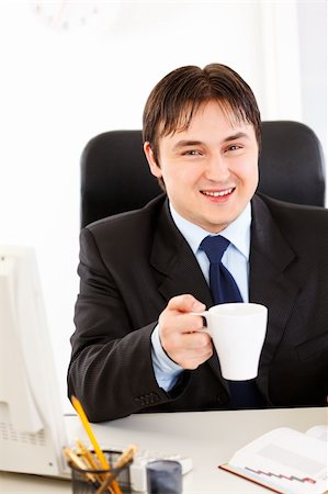 simsearch:400-05900668,k - Smiling business man  sitting at office desk  and holding cup of tea in hand Stock Photo - Budget Royalty-Free & Subscription, Code: 400-04305058