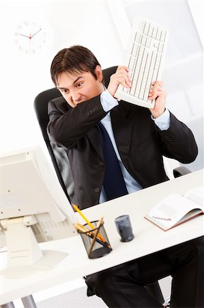 simsearch:400-05900668,k - Angry  business man sitting at office desk and destroying computer using keyboard Stock Photo - Budget Royalty-Free & Subscription, Code: 400-04305076