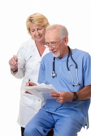 Woman doctor looking over seated male surgeon's notes. They are in discussion.  She is wearing a white coat, while he is in blue scrubs. Isolated on white background. Photographie de stock - Aubaine LD & Abonnement, Code: 400-04306107