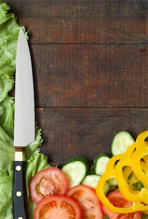 Kitchen knife and sliced vegetables lying on wooden surface with copy space Foto de stock - Super Valor sin royalties y Suscripción, Código: 400-04308026