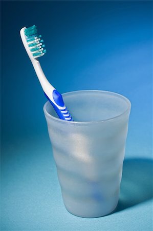 simsearch:400-04552289,k - Tooth brush in matte plastic glass over clear blue background. Foto de stock - Super Valor sin royalties y Suscripción, Código: 400-04309663