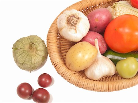 Overhead shot on white background of nutritious fresh vegetables - garlic, tomatoes, tomatillo, potatoes - in a basket. Close crop. Foto de stock - Super Valor sin royalties y Suscripción, Código: 400-04300129