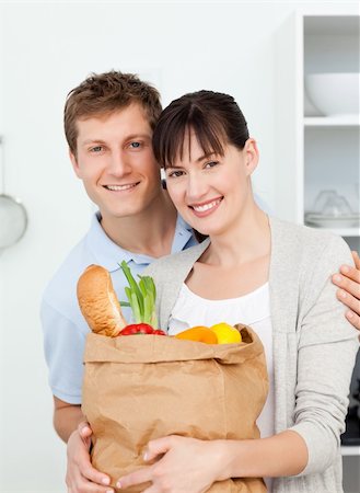 Lovely couple looking at the camera with their shoping bags at home Stock Photo - Budget Royalty-Free & Subscription, Code: 400-04300884