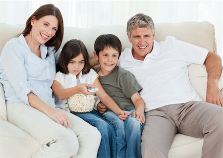 family on sofa popcorn - Family watching tv while they are eating popcorn Stock Photo - Budget Royalty-Free & Subscription, Code: 400-04301991