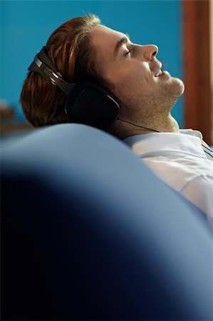 simsearch:6108-08725387,k - caucasian adult man relaxing on sofa with headphones. Vertical shape, side view, copy space Stock Photo - Budget Royalty-Free & Subscription, Code: 400-04302862