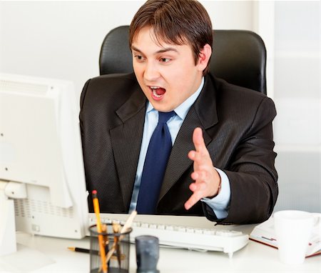 simsearch:400-05900668,k - Shocked modern businessman sitting at office desk and looking at computer monitor Stock Photo - Budget Royalty-Free & Subscription, Code: 400-04315465