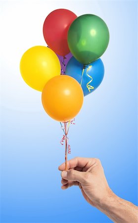 simsearch:400-04713054,k - Hand holding colorful air balloons over blue background Photographie de stock - Aubaine LD & Abonnement, Code: 400-04317198