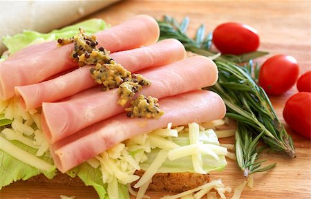 simsearch:400-07407920,k - Tasty open sandwich with green lettuce, grated cheese, smoked ham and wholegrain mustard on wholewheat bread with rosemary and tomatoes on chopping board Photographie de stock - Aubaine LD & Abonnement, Code: 400-04317845