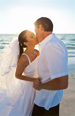 Married couple, bride and groom, kissing at sunset on a beautiful tropical beach wedding Foto de stock - Super Valor sin royalties y Suscripción, Código: 400-04310599