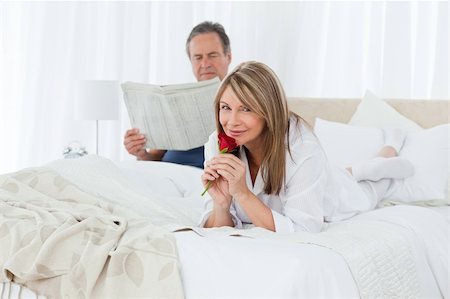 simsearch:400-04151970,k - Happy woman with her rose while her husband is reading a newspaper at home Fotografie stock - Microstock e Abbonamento, Codice: 400-04310933