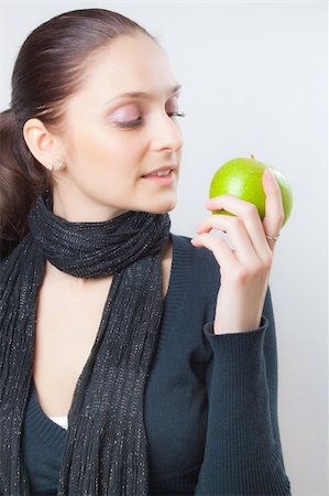 Beautiful elegant young lady with a charming smile and soft relaxing expression looking at fresh ripe green apple  in her hand Stock Photo - Budget Royalty-Free & Subscription, Code: 400-04311976