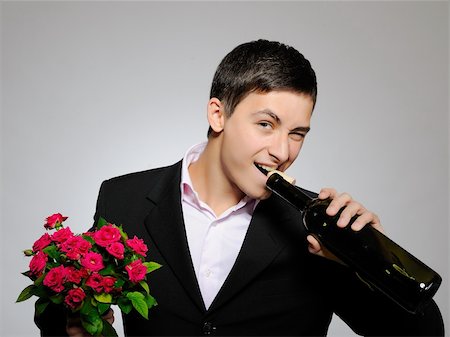 simsearch:400-05294518,k - Handsome romantic young man holding rose flower and vine bottle  prepared for a date. gray background Fotografie stock - Microstock e Abbonamento, Codice: 400-04313881