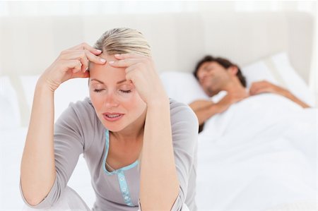 Attractive woman having a headache while her husband is sleeping at home Stock Photo - Budget Royalty-Free & Subscription, Code: 400-04324689