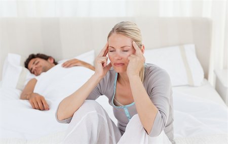 Attractive woman having a headache while her husband is sleeping at home Stock Photo - Budget Royalty-Free & Subscription, Code: 400-04324690
