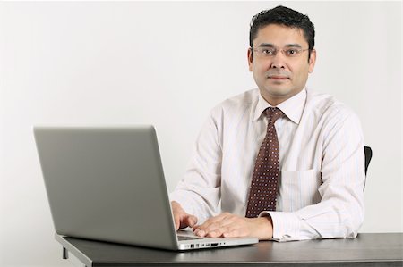 simsearch:400-05265698,k - Photo of an Indian male happy at work sitting in front of a laptop. Foto de stock - Super Valor sin royalties y Suscripción, Código: 400-04325220