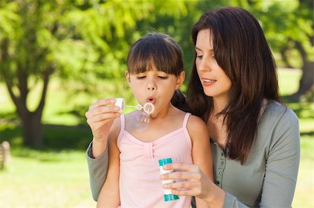 Girl blowing bubbles with her mother in the park Stock Photo - Budget Royalty-Free & Subscription, Code: 400-04327468