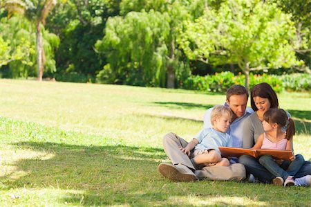 family photos in album - Family looking at their photo album in the park Stock Photo - Budget Royalty-Free & Subscription, Code: 400-04327491