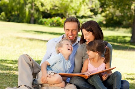 family photos in album - Family looking at their photo album in the park Stock Photo - Budget Royalty-Free & Subscription, Code: 400-04327492