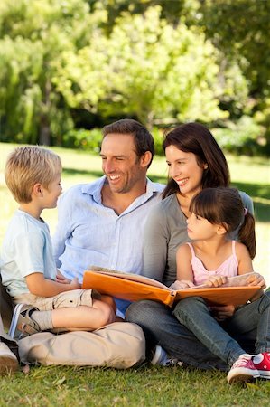 family photos in album - Family looking at their photo album in the park Stock Photo - Budget Royalty-Free & Subscription, Code: 400-04327493