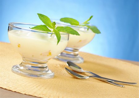Mango cream cheese dessert with mint in glass bowl with a dessert spoons on yellow table mat with blue background (Selective Focus, Focus on the front of the glass and the leaves) Stock Photo - Budget Royalty-Free & Subscription, Code: 400-04327915