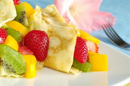simsearch:400-04859746,k - Crepes filled with fresh fruits (strawberry, kiwi, mango, watermelon) with a pink gladiolus and a fork in the background (Selective Focus, Focus on the strawberry half and the crepe) Foto de stock - Super Valor sin royalties y Suscripción, Código: 400-04327979