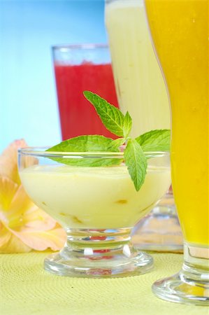 Light summer cream-cheese-mango dessert garnished with mint leaves with mango, pineapple and watermelon smoothies and gladiolus flower (Selective Focus, Focus on the mint leaf and the front of the bowl) Foto de stock - Royalty-Free Super Valor e Assinatura, Número: 400-04327988