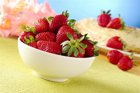 Fresh strawberries in white ceramic bowl with crepes and pink gladiolus flowers in the background (Selective Focus, Focus on the front of the strawberries) Foto de stock - Royalty-Free Super Valor e Assinatura, Número: 400-04327989