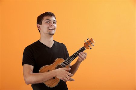 simsearch:400-05745955,k - Latino teen playing a ukulele on an orange background Foto de stock - Royalty-Free Super Valor e Assinatura, Número: 400-04328155