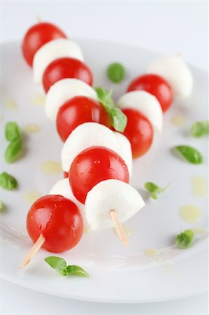 Cherry tomatoes and mozzarella on skewers, garnished with basil leaves and olive oil Stock Photo - Budget Royalty-Free & Subscription, Code: 400-04328407