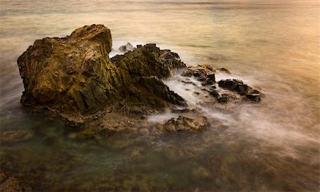 simsearch:400-06137661,k - Slow exposure blurs the waves in the ocean as they break over a rocky outcrop at sunset Stock Photo - Budget Royalty-Free & Subscription, Code: 400-04320416