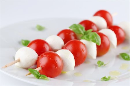 Cherry tomatoes and mozzarella on skewers, garnished with basil leaves and olive oil Stock Photo - Budget Royalty-Free & Subscription, Code: 400-04321837