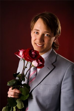 simsearch:400-04323304,k - Young man wearing suit holding roses over red background Stock Photo - Budget Royalty-Free & Subscription, Code: 400-04322194