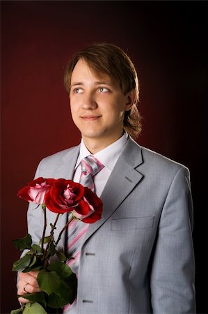 roses only - Young man wearing suit holding roses over red background Stock Photo - Budget Royalty-Free & Subscription, Code: 400-04322198