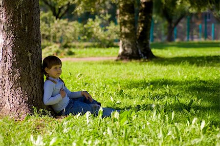 Pensive little girl sitting in the grass near tree Stockbilder - Microstock & Abonnement, Bildnummer: 400-04322192