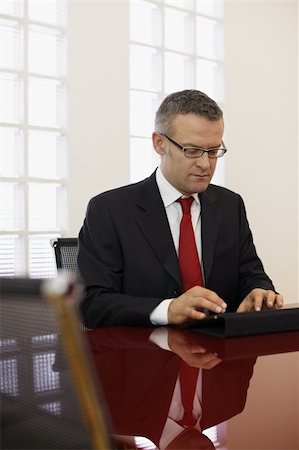 simsearch:628-05817499,k - caucasian mid adult male manager typing on tablet pc in meeting room. Vertical shape, side view, copy space Photographie de stock - Aubaine LD & Abonnement, Code: 400-04323710