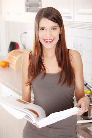 Young beautiful woman reading cookbook in the kitchen, looking for recipe Stock Photo - Budget Royalty-Free & Subscription, Code: 400-04335894
