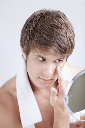 A young man looks in the mirror in the bathroom Stock Photo - Budget Royalty-Free & Subscription, Code: 400-04336294