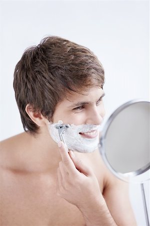 Young man shaving at the mirror on a white background Stock Photo - Budget Royalty-Free & Subscription, Code: 400-04336307